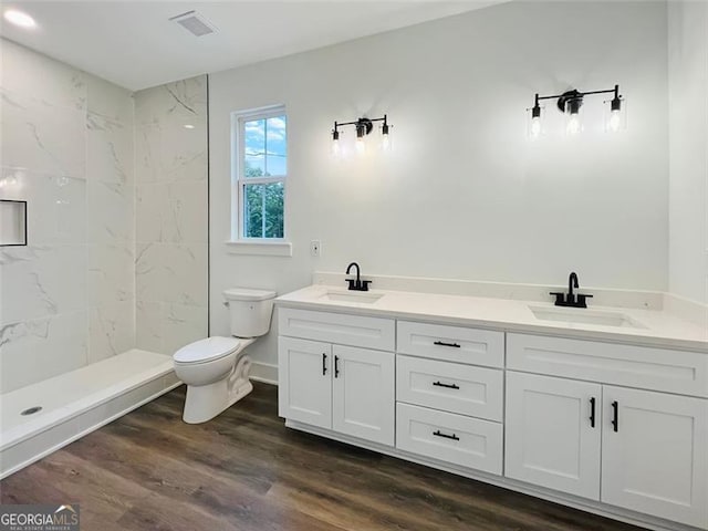 bathroom with double vanity, visible vents, a sink, and wood finished floors