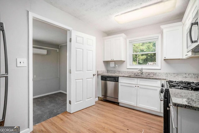 kitchen featuring light stone counters, white cabinetry, stainless steel appliances, and a sink
