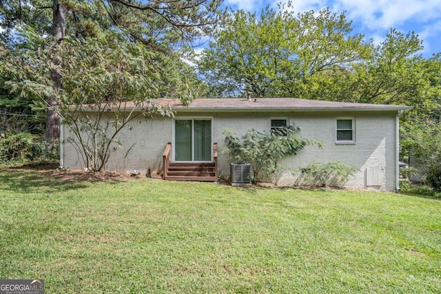 rear view of house with central air condition unit, a yard, entry steps, and brick siding