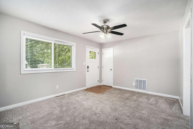foyer entrance featuring baseboards, a ceiling fan, visible vents, and carpet floors
