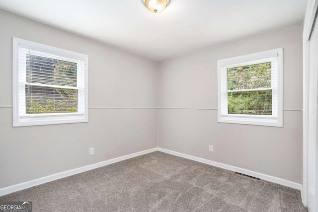 empty room featuring baseboards, visible vents, and carpet