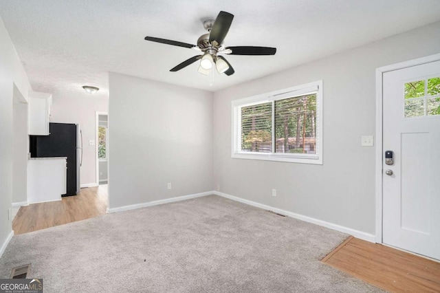 interior space with baseboards, visible vents, light colored carpet, and ceiling fan