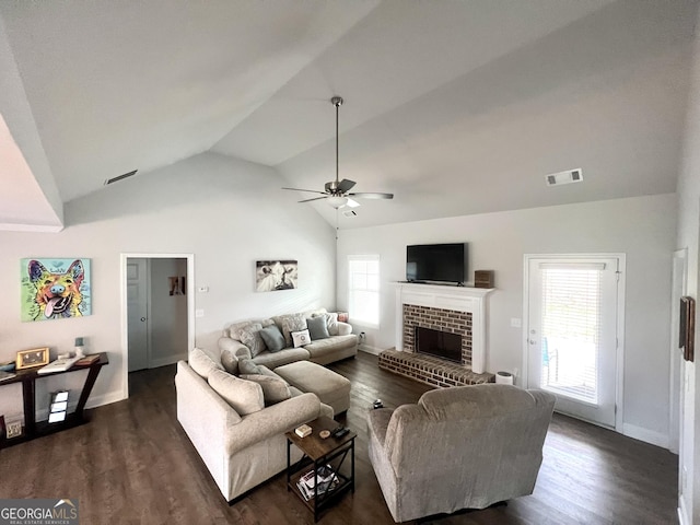 living room featuring a brick fireplace, dark wood-type flooring, a healthy amount of sunlight, and ceiling fan