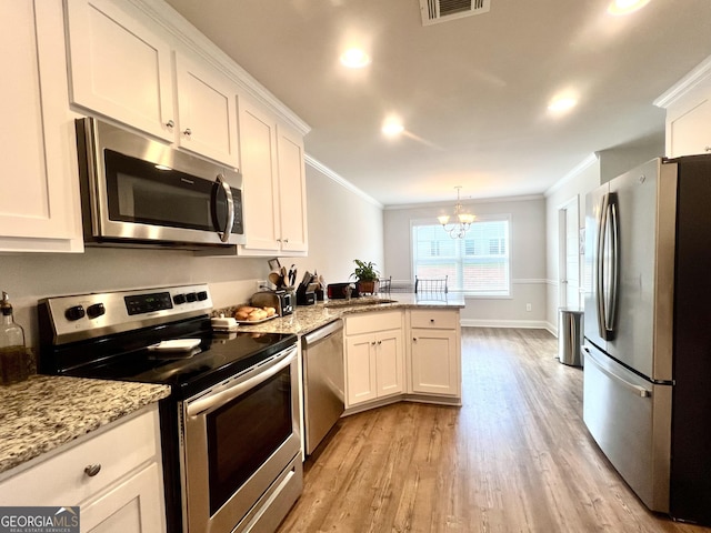 kitchen with hanging light fixtures, white cabinetry, appliances with stainless steel finishes, and an inviting chandelier