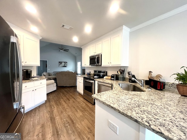 kitchen featuring stainless steel appliances, kitchen peninsula, sink, and white cabinets