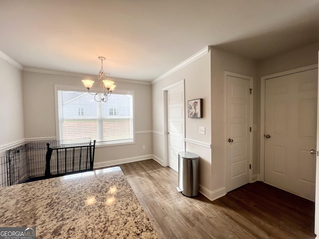 dining room featuring dark hardwood / wood-style flooring, ornamental molding, and an inviting chandelier