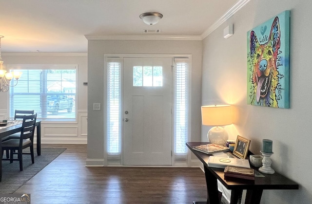 entryway featuring dark hardwood / wood-style flooring, ornamental molding, and a chandelier