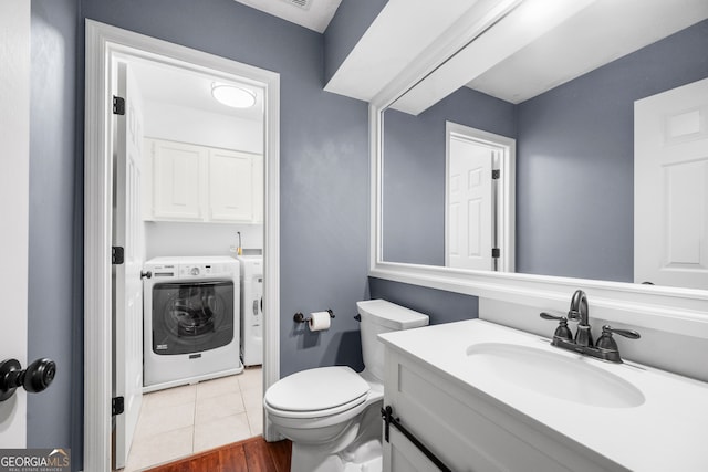 bathroom with tile patterned flooring, vanity, toilet, and washer and dryer