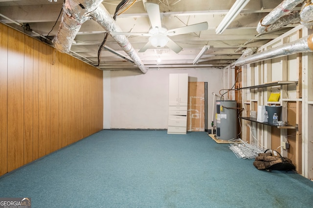 basement featuring wooden walls, ceiling fan, electric water heater, and carpet floors