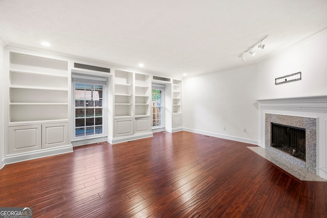 unfurnished living room with built in shelves, crown molding, and dark wood-type flooring