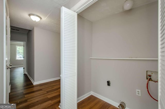 clothes washing area with a textured ceiling, electric dryer hookup, hookup for a washing machine, and dark wood-type flooring