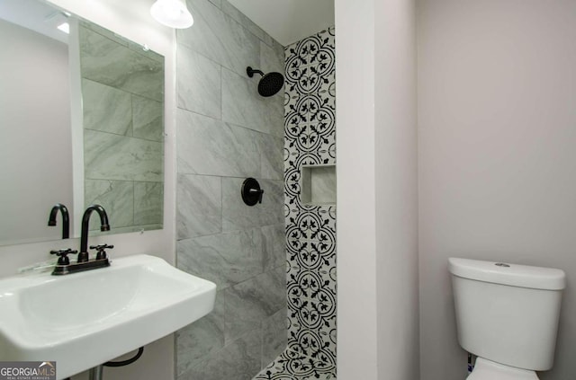 bathroom with sink, toilet, and tiled shower