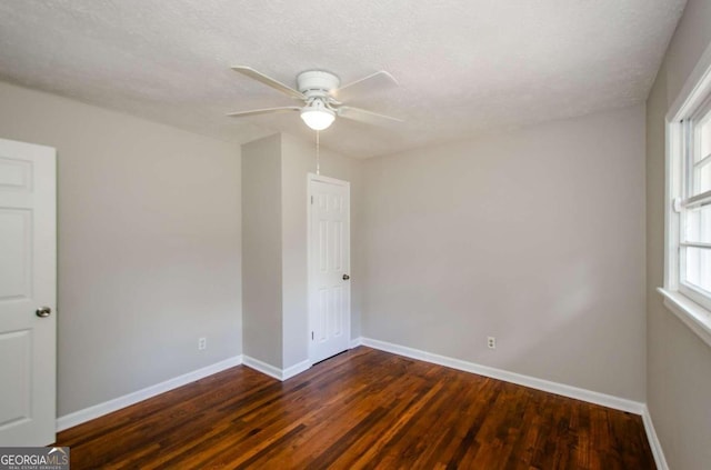 empty room with a textured ceiling, dark hardwood / wood-style floors, and ceiling fan