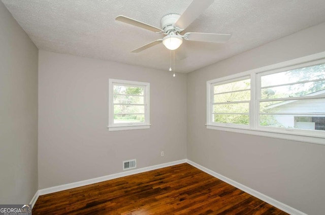 spare room with a textured ceiling, dark hardwood / wood-style floors, and ceiling fan