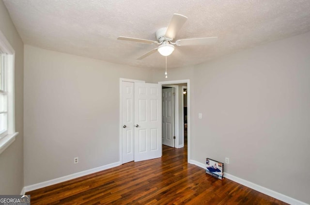 unfurnished room with a textured ceiling, ceiling fan, and dark hardwood / wood-style flooring