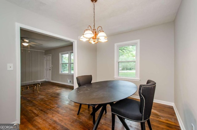 dining area with ceiling fan with notable chandelier, a wealth of natural light, and dark wood-type flooring