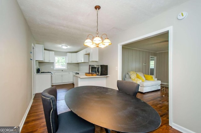 dining space featuring an inviting chandelier, a textured ceiling, and dark hardwood / wood-style floors