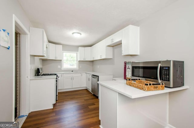 kitchen featuring kitchen peninsula, a textured ceiling, white cabinetry, stainless steel appliances, and dark hardwood / wood-style flooring