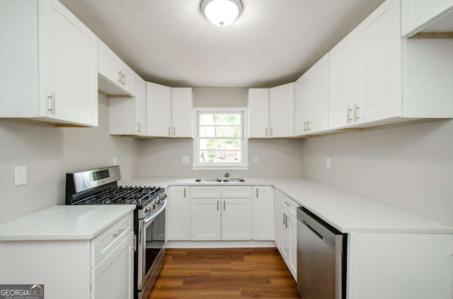 kitchen with a textured ceiling, sink, white cabinets, stainless steel appliances, and dark hardwood / wood-style flooring