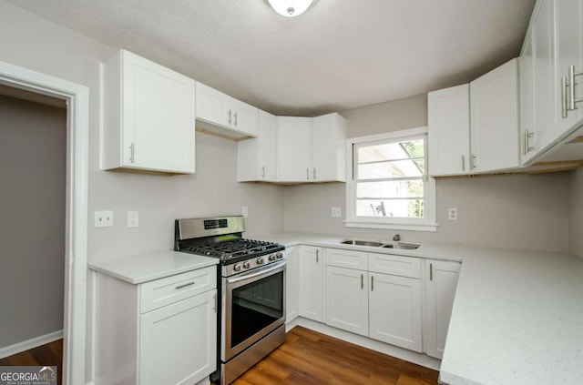 kitchen with white cabinets, stainless steel range with gas stovetop, dark wood-type flooring, and sink