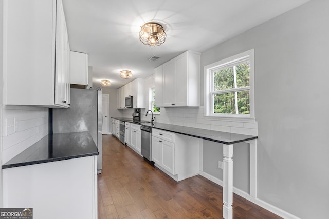 kitchen featuring appliances with stainless steel finishes, dark countertops, and white cabinets