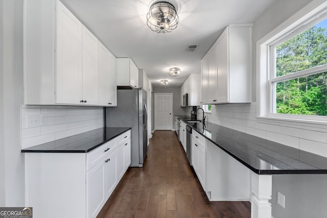 kitchen featuring dark countertops, white cabinetry, visible vents, and decorative backsplash