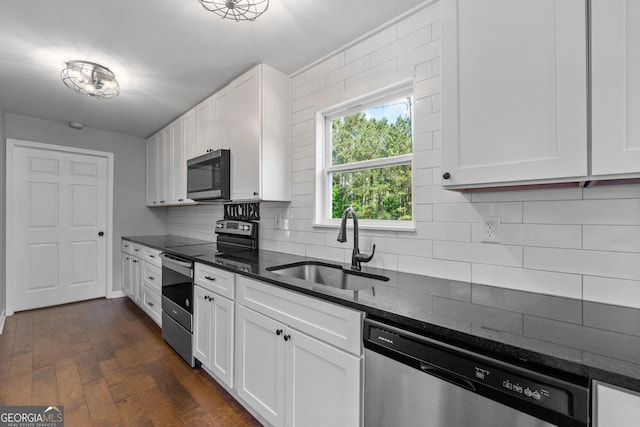 kitchen with a sink, white cabinetry, appliances with stainless steel finishes, dark stone counters, and tasteful backsplash