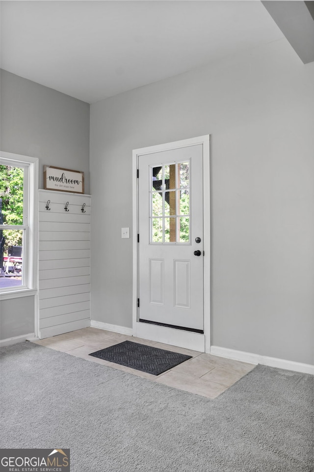 entryway with baseboards and light colored carpet