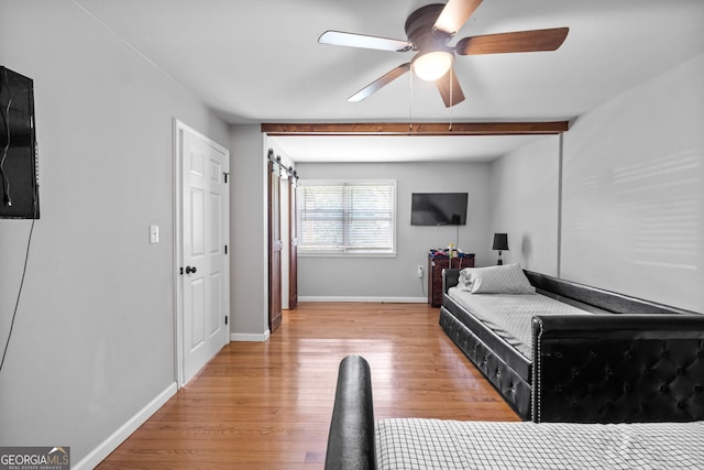 bedroom with light wood-type flooring, a ceiling fan, baseboards, and beamed ceiling