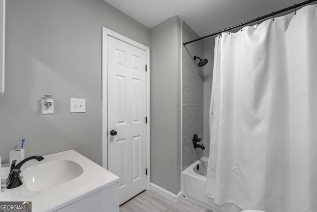 bathroom with wood finished floors, shower / bath combo, and a sink