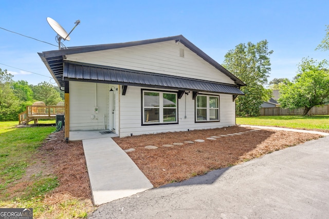 view of front of property with a porch, metal roof, a front lawn, and fence