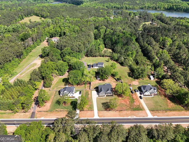 birds eye view of property with a water view and a wooded view