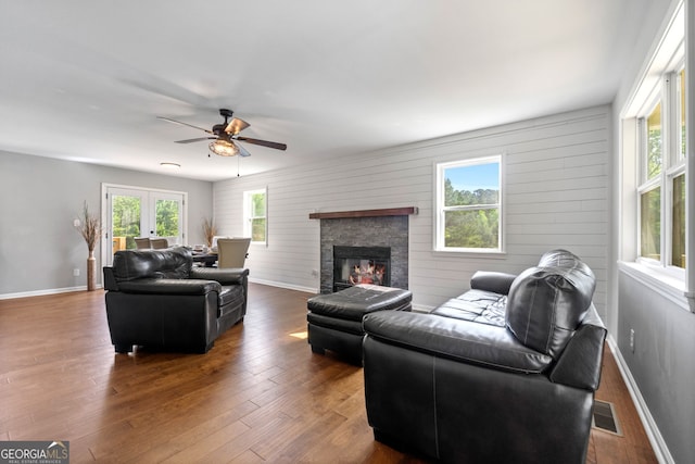 living room with baseboards, a fireplace, visible vents, and wood finished floors