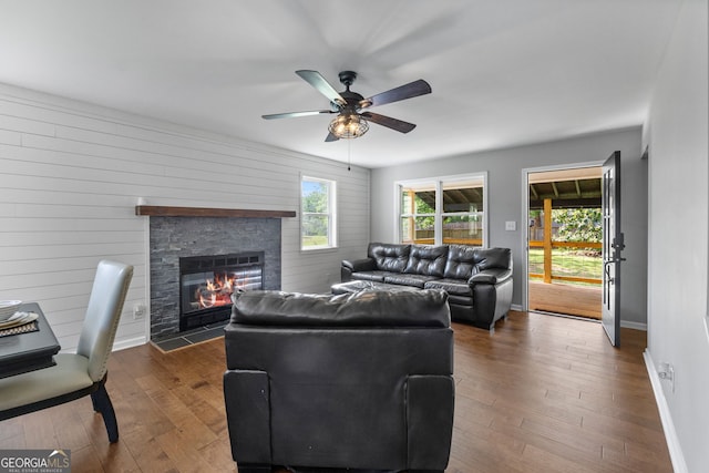 living room with plenty of natural light, a fireplace, baseboards, and dark wood-type flooring