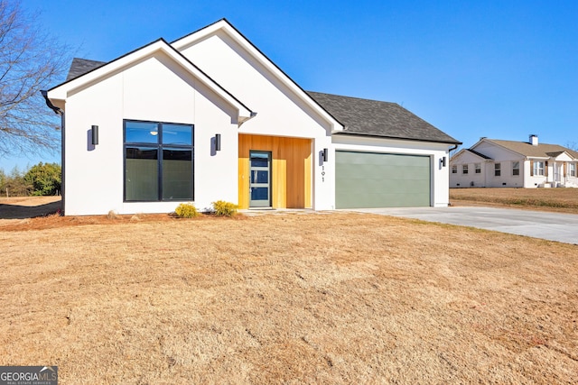 modern farmhouse style home featuring a shingled roof, a front yard, driveway, and an attached garage