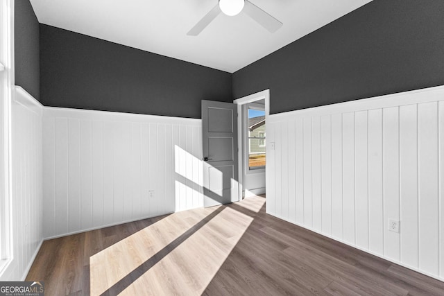 unfurnished room featuring a ceiling fan, a wainscoted wall, and wood finished floors