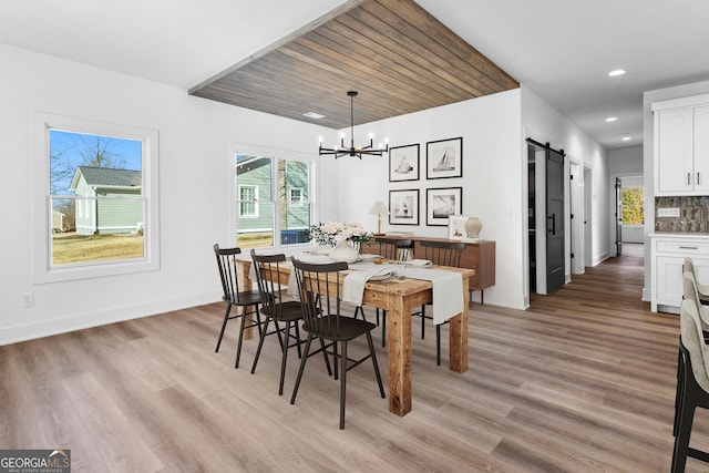 dining area with a notable chandelier, recessed lighting, a barn door, light wood-type flooring, and baseboards