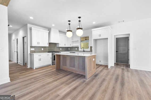 kitchen featuring gas stove, white cabinets, custom range hood, and open shelves