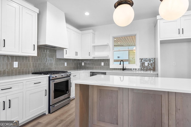 kitchen featuring tasteful backsplash, stainless steel appliances, light countertops, premium range hood, and a sink