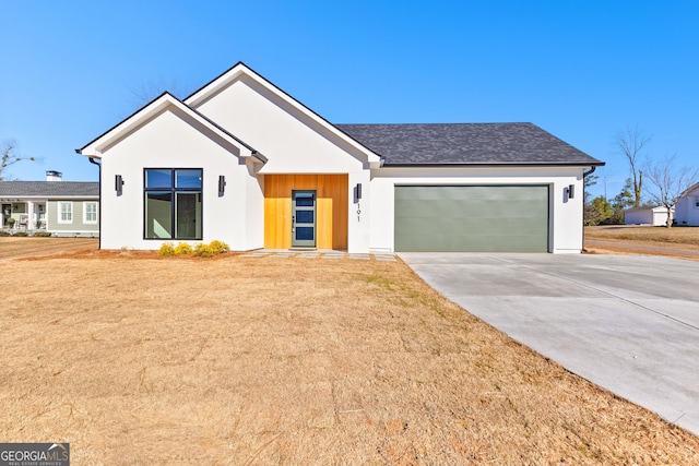 modern farmhouse featuring a garage, concrete driveway, and a front lawn