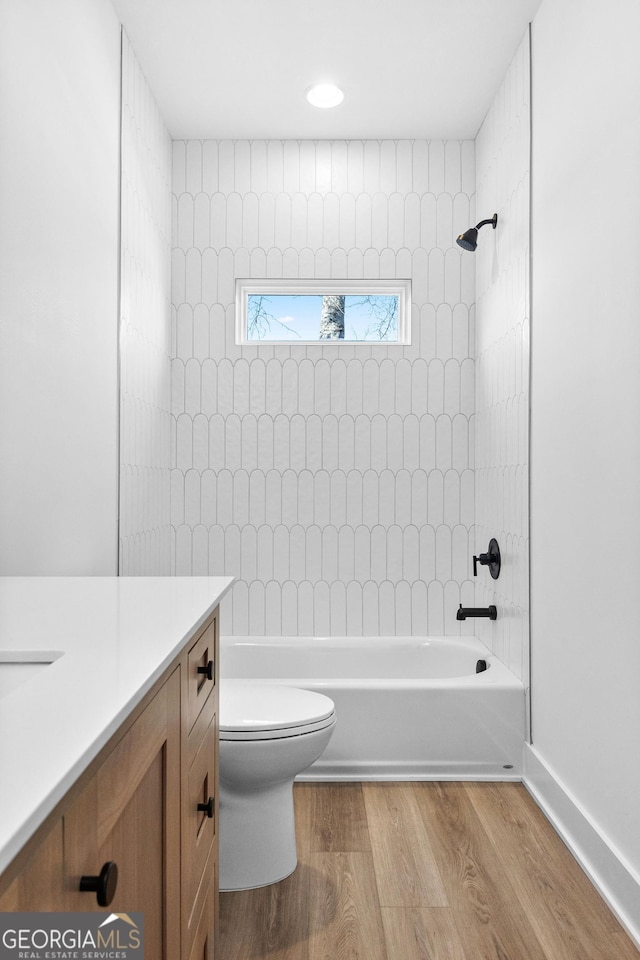 bathroom featuring toilet, vanity, wood finished floors, and shower / bathtub combination