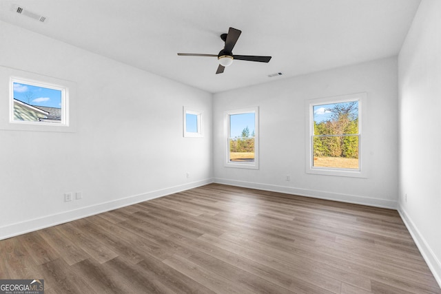 empty room with a ceiling fan, visible vents, baseboards, and wood finished floors