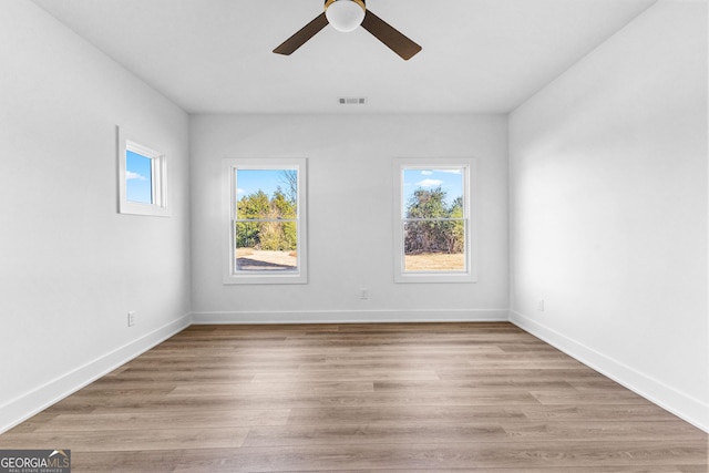 empty room featuring a wealth of natural light, light wood-style flooring, and baseboards