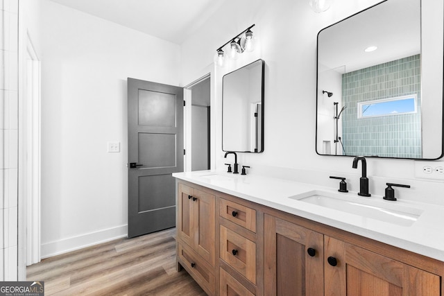 bathroom featuring double vanity, wood finished floors, a sink, and baseboards