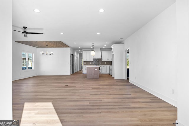 unfurnished living room featuring light wood-type flooring, baseboards, ceiling fan with notable chandelier, and recessed lighting