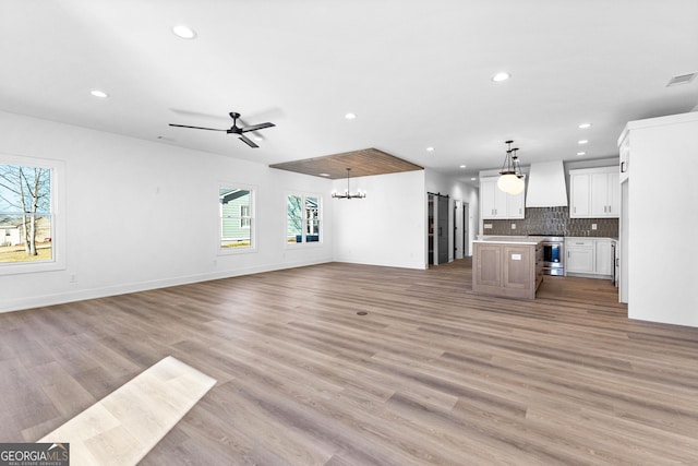 unfurnished living room with recessed lighting, baseboards, visible vents, light wood-style floors, and ceiling fan with notable chandelier