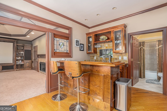 bar with light hardwood / wood-style floors and crown molding