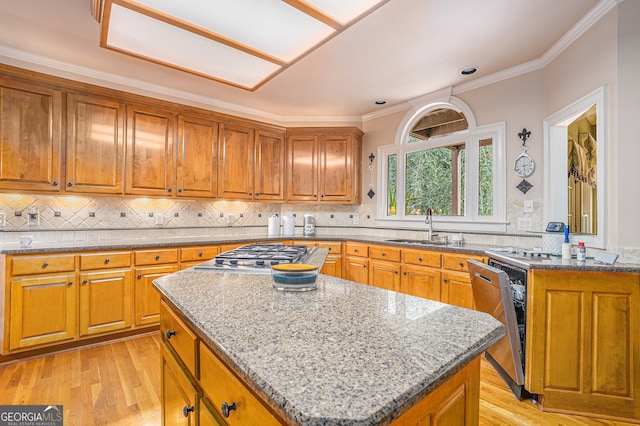 kitchen featuring a center island, sink, light hardwood / wood-style flooring, stainless steel appliances, and crown molding