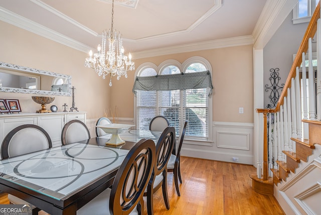 dining room featuring ornamental molding, light hardwood / wood-style floors, and a notable chandelier