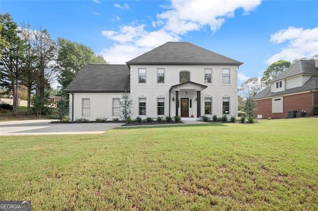 colonial-style house featuring a front yard and central AC